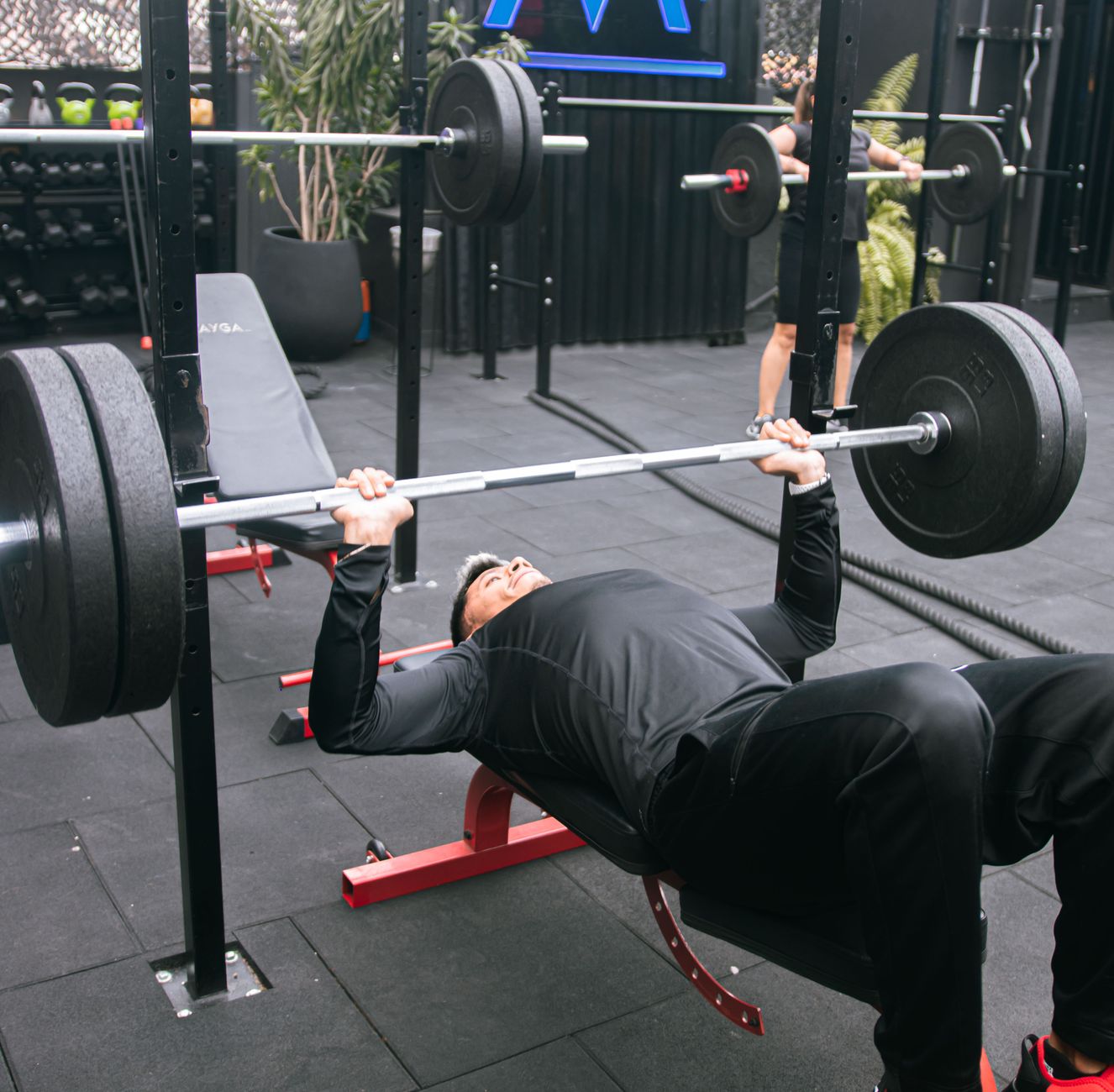 Man performing a close grip bench press with an EZ curl bar on a weight bench