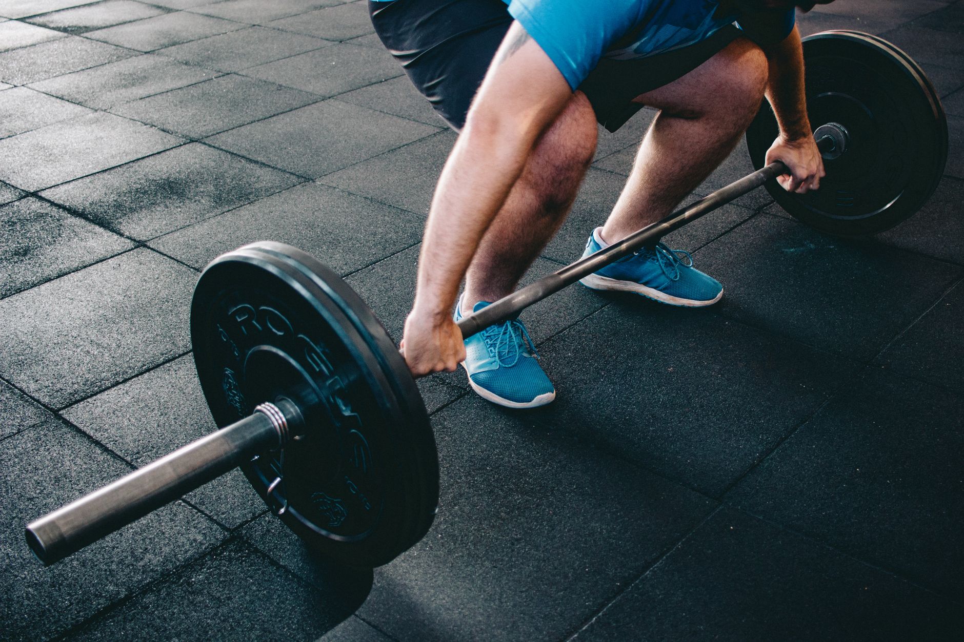 A home gym setup with black rubber flooring and weightlifting equipment.