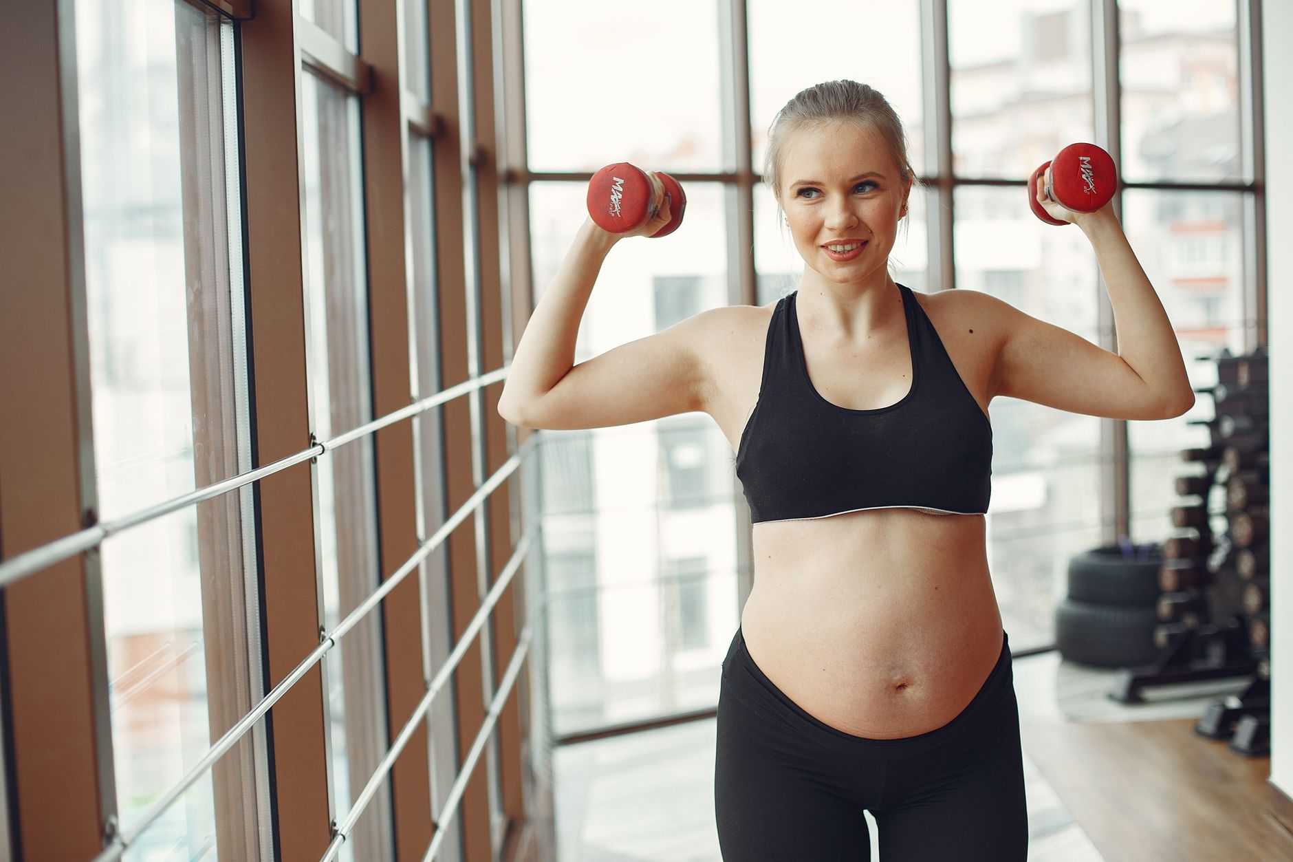 A pregnant woman gently lifting a dumbbell