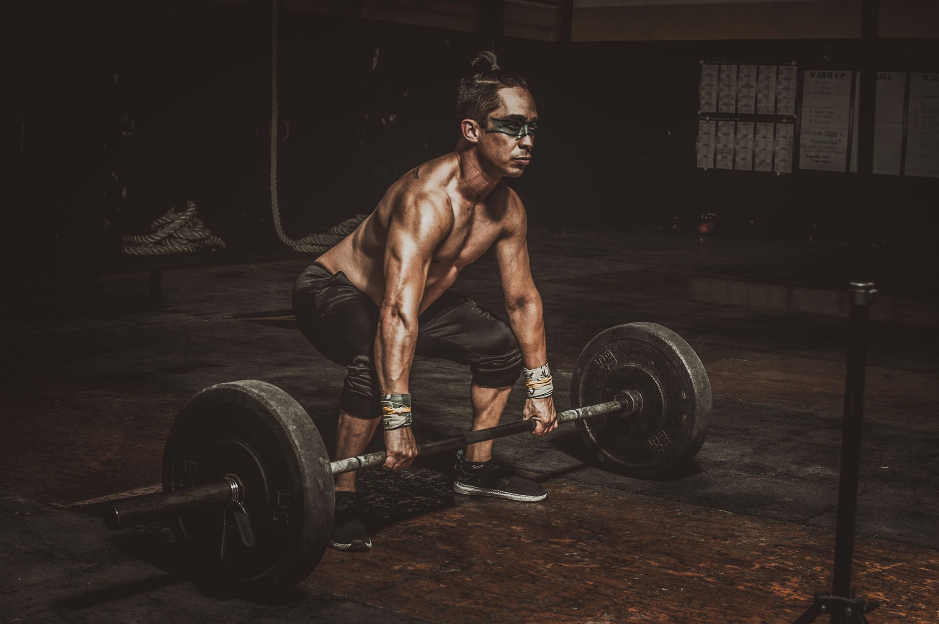 Man performing a heavy deadlift with proper form in a home gym, engaging full body muscles.