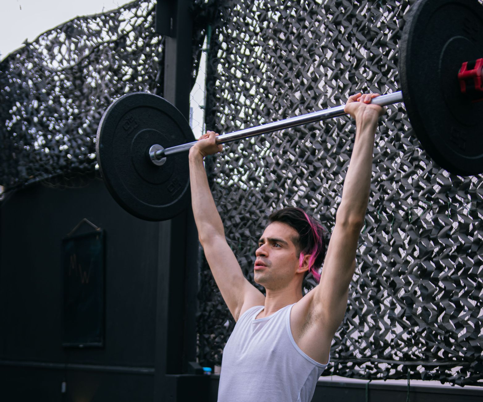 A man performing an overhead press with a barbell